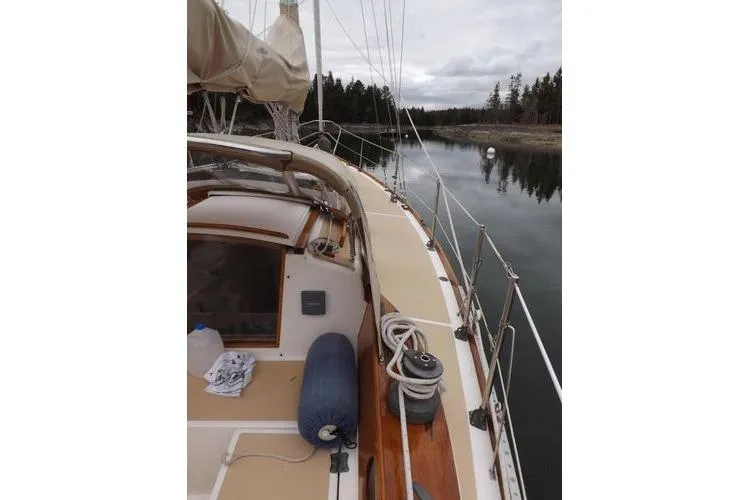 Slide: The Image of 1987 Cape Dory 36 sailboat deck view, moored in calm waters with forested shoreline. - 11