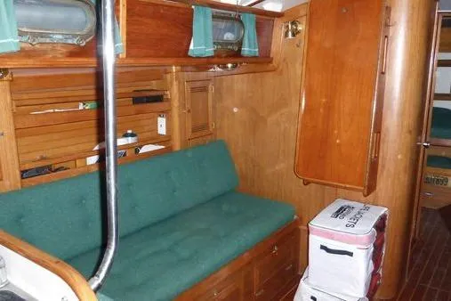 Slide: The Image of 1987 Cape Dory 36 interior with green cushioned seating, wooden cabinetry, and nautical decor. - 33