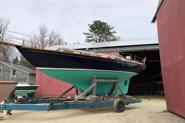 Slide: The Image of 1987 Cape Dory 36 sailboat on trailer, displayed outdoors near red buildings. - 49
