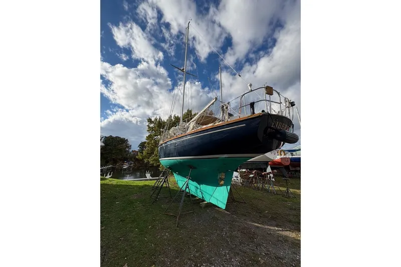 Slide: The Image of 1987 Cape Dory 36 sailboat on land, blue hull, under a partly cloudy sky. - 50