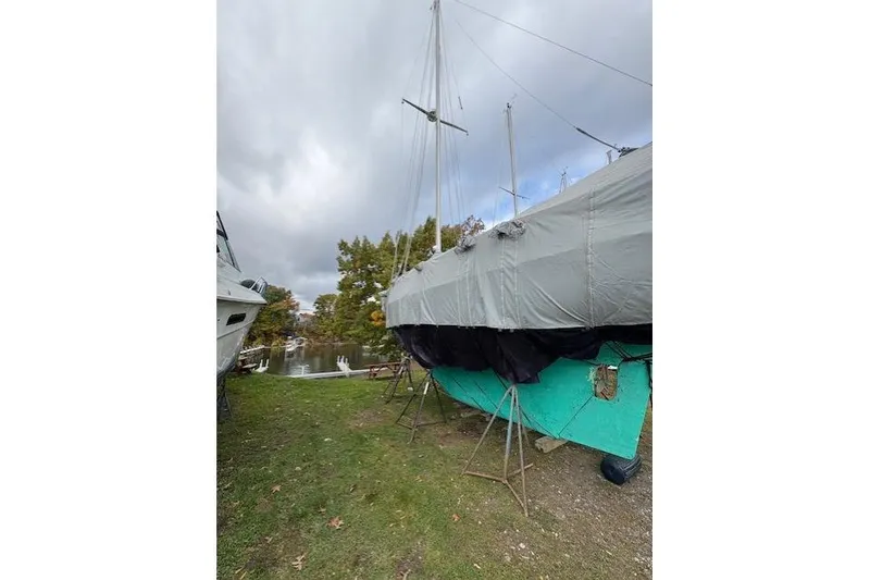 Slide: The Image of 1987 Cape Dory 36 sailboat covered and docked on grassy shore. - 53