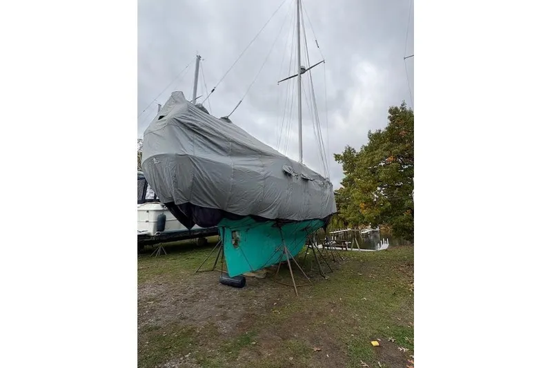 Slide: The Image of 1987 Cape Dory 36 sailboat covered and stored on land, overcast sky. - 55