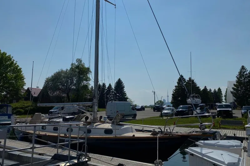Slide: The Image of 1987 Cape Dory 36 sailboat docked at marina with trees and vehicles in background. - 9
