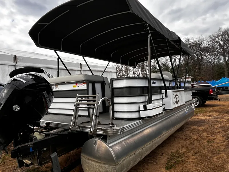 The Image of 2021 Crest 22 SLC pontoon boat with black canopy on dry land. - 1