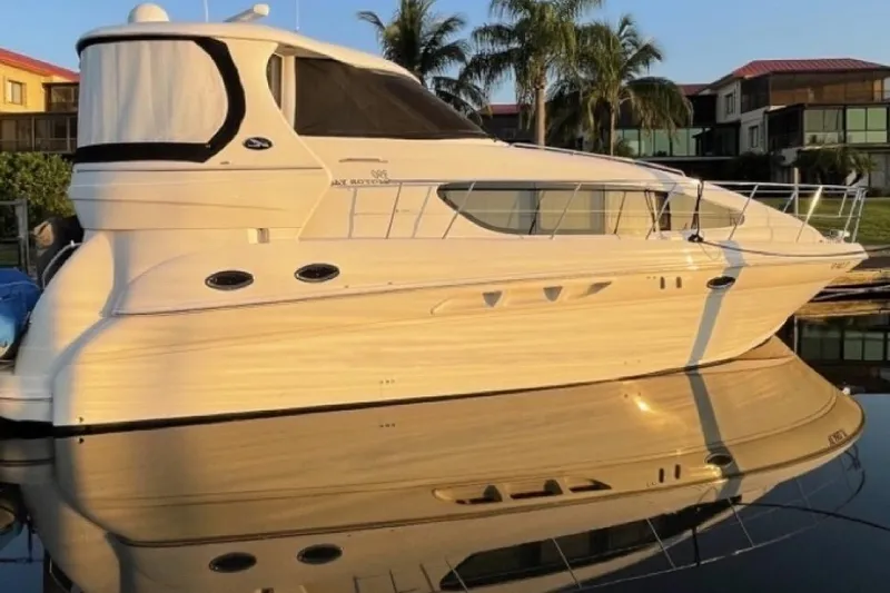 The Image of 2004 Sea Ray 390 Motor Yacht docked, reflecting on calm water, with palm trees in background. - 1