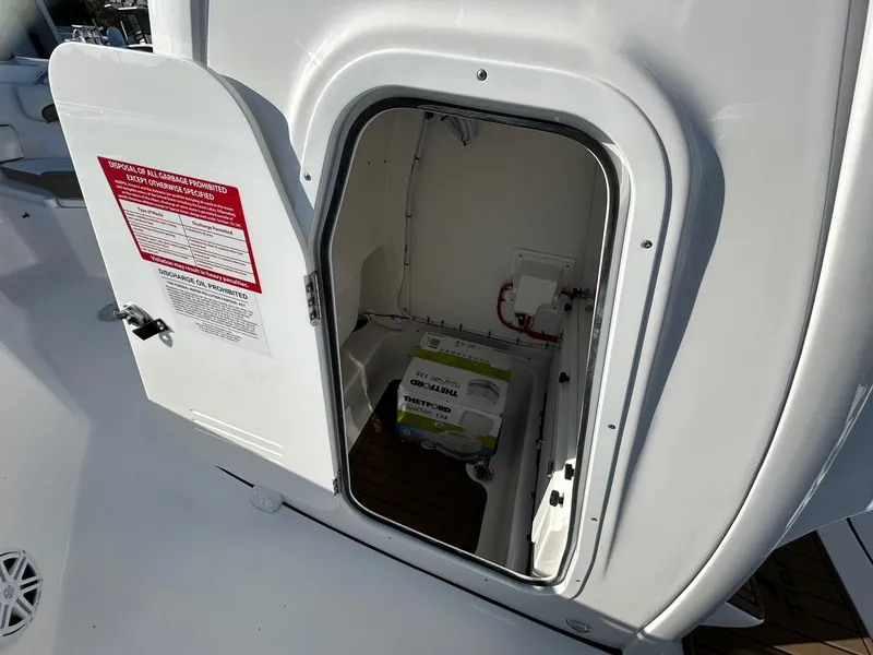 Slide: The Image of 2025 Tidewater 232 LXF boat storage compartment with open door. - 23