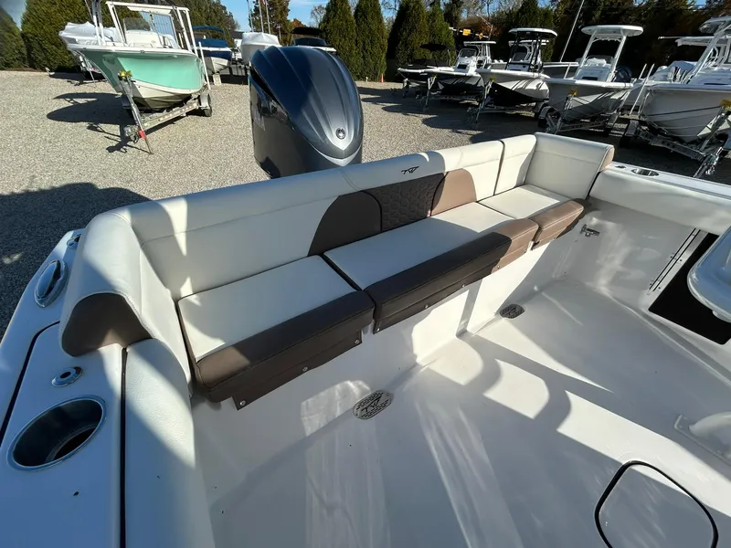 Slide: The Image of 2025 Tidewater 232 LXF boat with cushioned seating and outboard motor in a marina. - 38