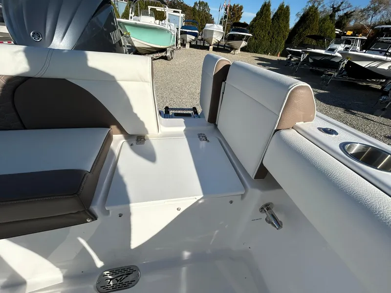 Slide: The Image of 2025 Tidewater 232 LXF boat interior with seating and storage, parked among other boats. - 49