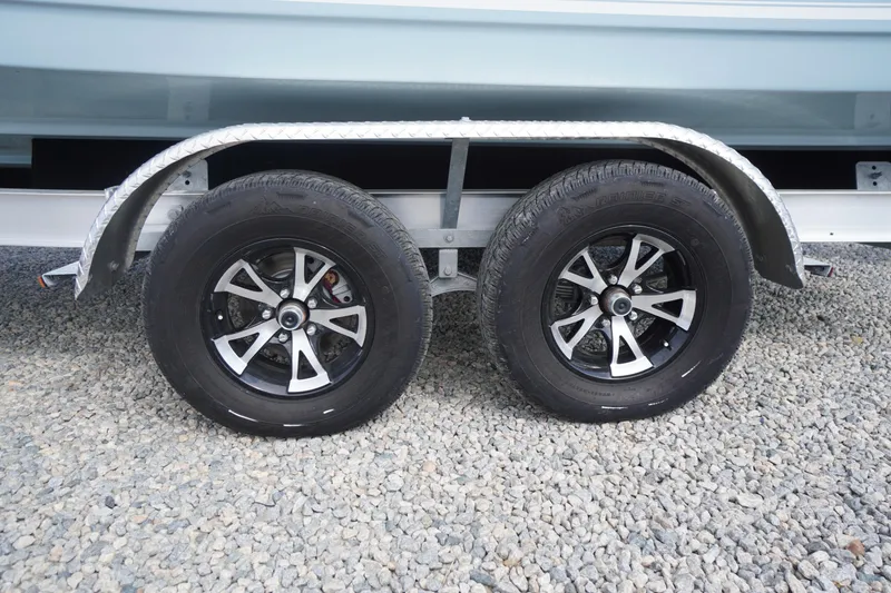 Slide: The Image of Trailer wheels of a 2026 Tidewater 232 LXF boat on gravel surface. - 72
