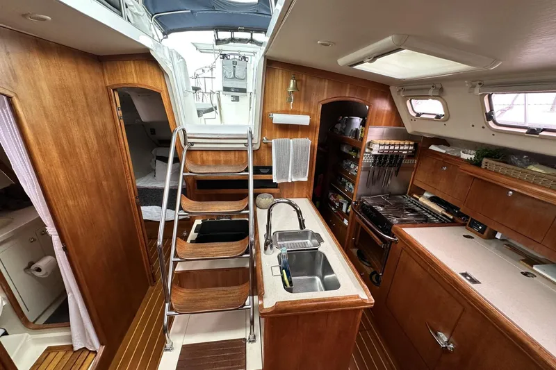 Slide: The Image of Interior of a 2002 Hunter 466 sailboat featuring a compact kitchen and wooden cabinetry. - 30