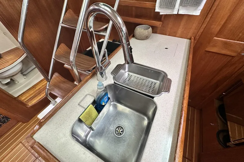 Slide: The Image of 2002 Hunter 466 yacht kitchen sink with faucet, sponge, and dish soap on countertop. - 33