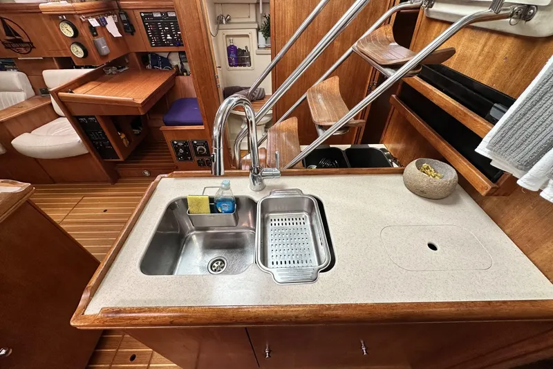 Slide: The Image of 2002 Hunter 466 yacht interior with kitchen sink, wooden cabinetry, and navigation station. - 34