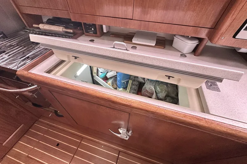 Slide: The Image of Open refrigerator in a 2002 Hunter 466 yacht kitchen, showing stored food items. - 37