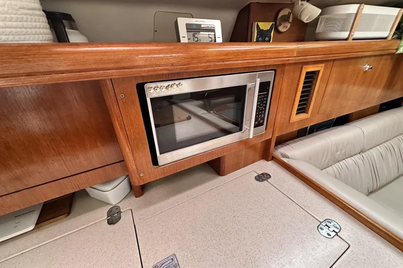 Slide: The Image of 2002 Hunter 466 yacht interior with microwave, wooden cabinetry, and cushioned seating. - 38