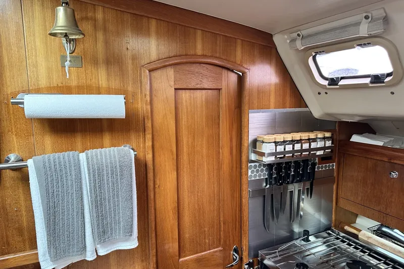Slide: The Image of Wood-paneled boat kitchen with spice rack, knives, and towels on a Hunter 466, 2002 model. - 40