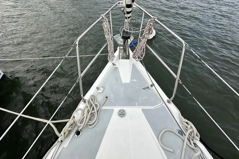 Slide: The Image of Bow of a 2002 Hunter 466 sailboat with ropes and railing on water. - 6