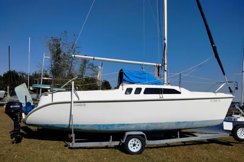 Slide: The Image of 1998 Hunter 240 sailboat on trailer with blue tarp and Tohatsu outboard motor. - 12
