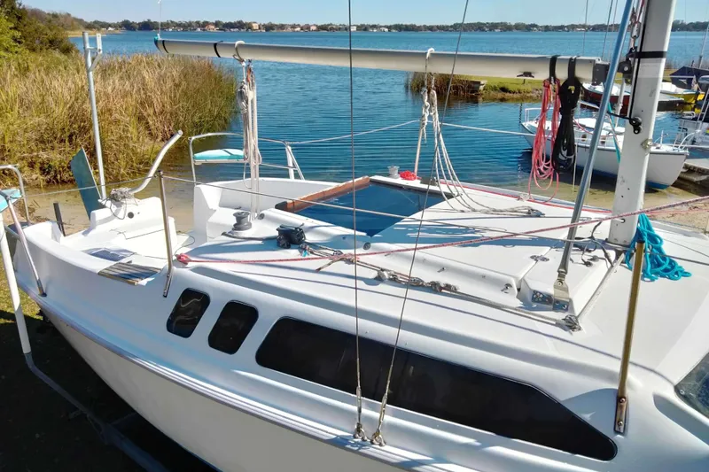 Slide: The Image of 1998 Hunter 240 sailboat docked by a serene lake with clear blue water. - 17