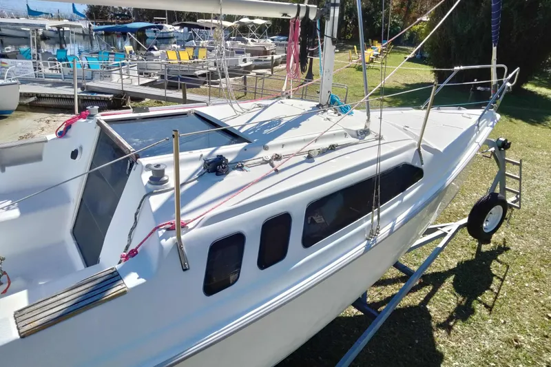 Slide: The Image of 1998 Hunter 240 sailboat on trailer, docked near marina with other boats in background. - 19