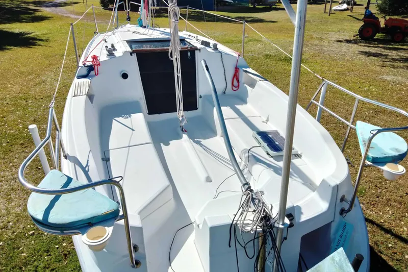 Slide: The Image of 1998 Hunter 240 sailboat with spacious deck, solar panel, and seating, parked on grass. - 23