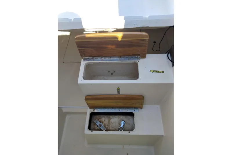 Slide: The Image of Storage compartments on a 1998 Hunter 240 boat, featuring wooden lids and rescue label. - 7