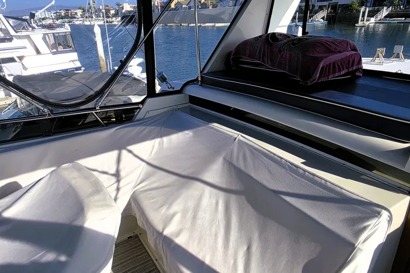 Slide: The Image of 1990 Californian 48 Cockpit Motor Yacht interior with cushioned seating and waterfront view. - 12
