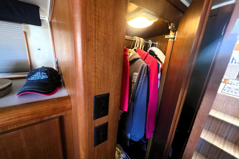 Slide: The Image of Cozy cabin closet in 1990 Californian 48 Cockpit Motor Yacht with hanging clothes and hats. - 32
