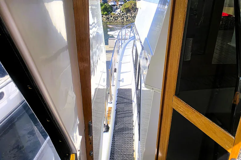Slide: The Image of 1990 Californian 48 Cockpit Motor Yacht docked near palm trees and rocky shoreline. - 62
