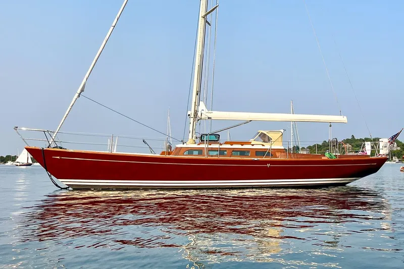 The Image of Red Morris M42 sailboat from 2011 on calm water, clear sky background. - 0