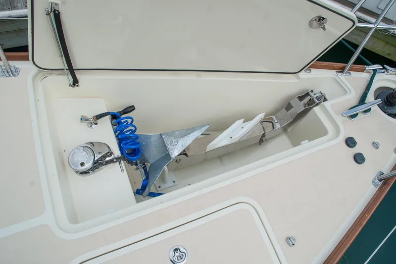 Slide: The Image of Anchor storage compartment on a 2011 Morris M42 sailboat, featuring a coiled blue hose. - 5