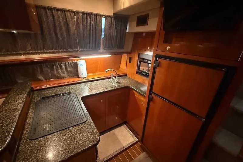 Slide: The Image of Luxurious 2005 Cruisers Yachts 405 Express Motoryacht kitchen with wood cabinetry and granite countertops. - 24
