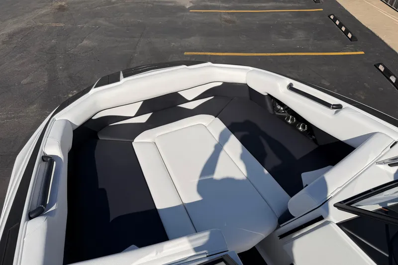Slide: The Image of 2025 Moomba Makai boat interior with white and black seating, parked on asphalt. - 25