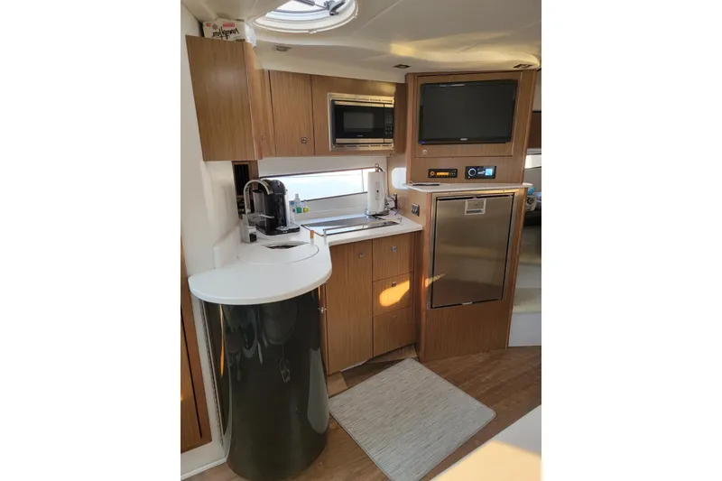 Slide: The Image of 2019 Cruisers Yachts 38 Express interior kitchen with modern appliances and wood cabinetry. - 13