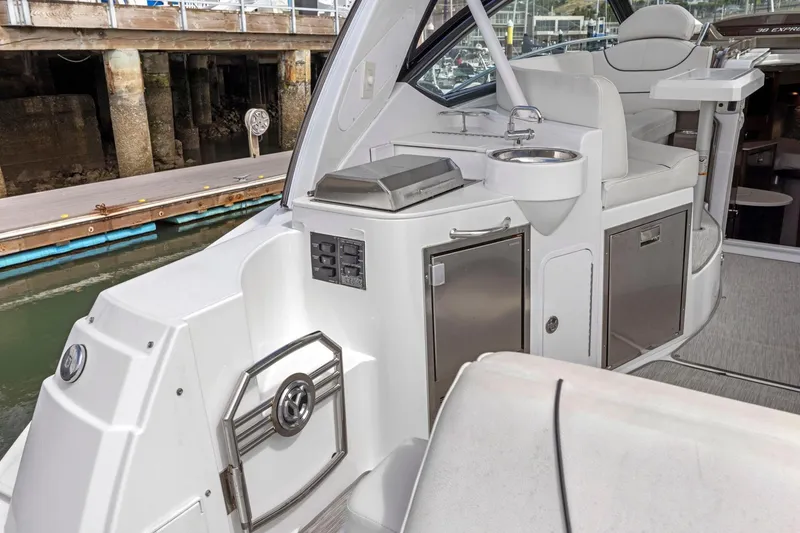 Slide: The Image of 2019 Cruisers Yachts 38 Express interior with kitchenette and seating, docked at marina. - 30
