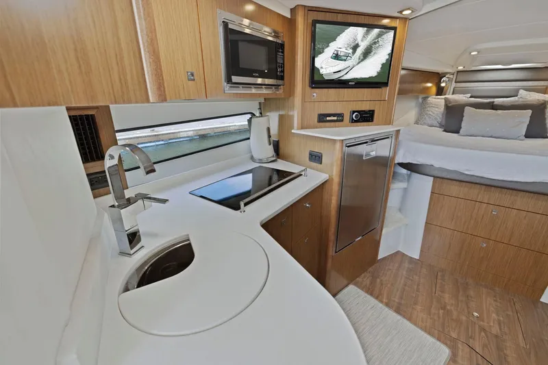 Slide: The Image of Interior of 2019 Cruisers Yachts 38 Express, featuring modern kitchen and cozy sleeping area. - 38