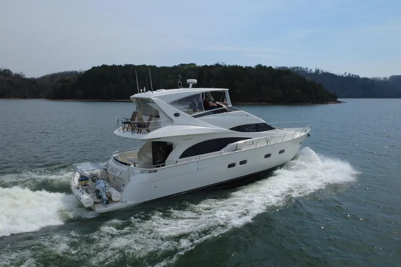 Slide: The Image of Luxury 2004 Marquis 59 yacht cruising on a serene lake with forested shoreline. - 10