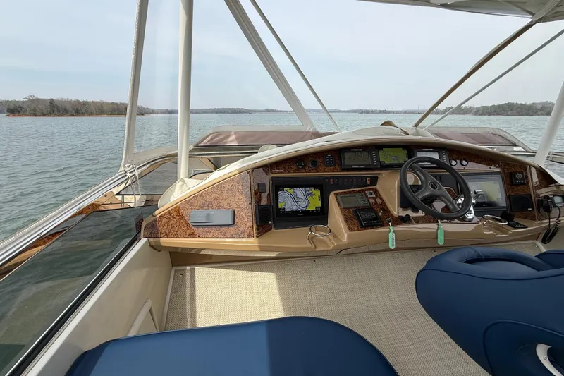 Slide: The Image of 2004 Marquis 59 yacht cockpit with navigation equipment and steering wheel on a calm lake. - 16