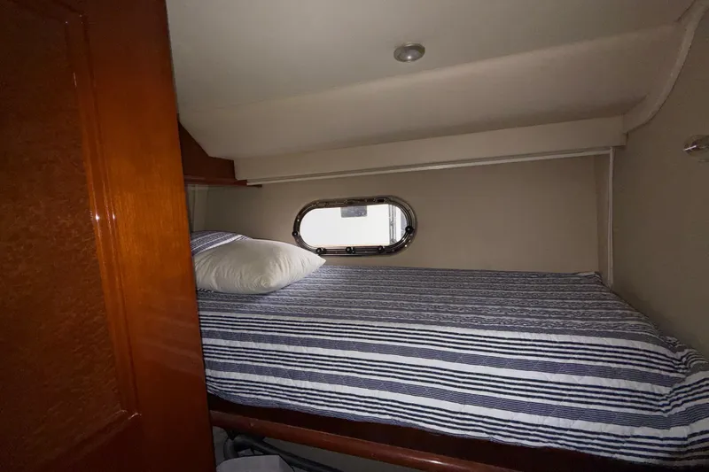 Slide: The Image of Cozy cabin interior of 2004 Marquis 59 yacht with striped bedding and porthole window. - 43