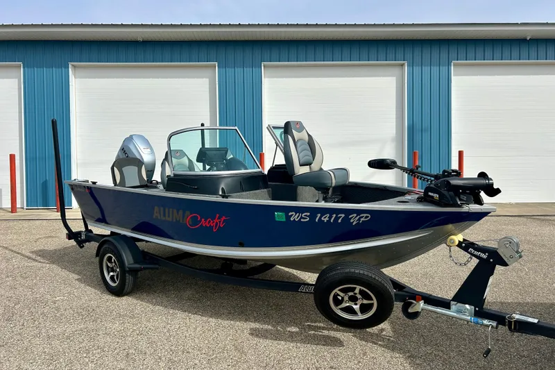 The Image of 2021 Alumacraft Classic 165 Sport boat on trailer, parked outside blue garage. - 0