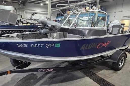 The Image of 2021 Alumacraft Classic 165 Sport boat in showroom, blue exterior, on trailer. - 1