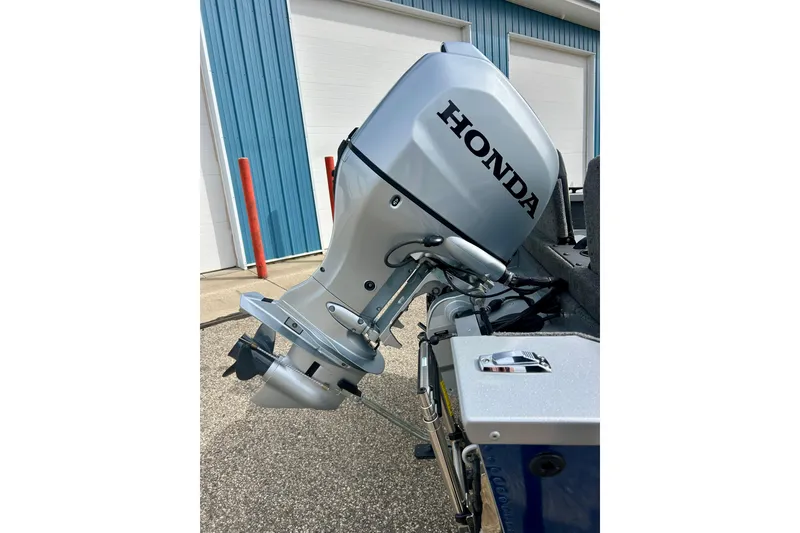 Slide: The Image of 2021 Alumacraft Classic 165 Sport with Honda outboard motor, parked near blue building. - 12