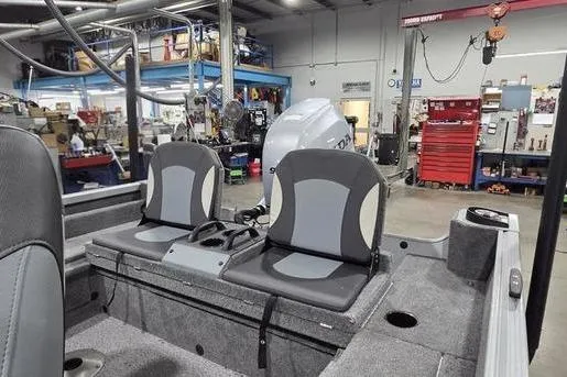 Slide: The Image of 2021 Alumacraft Classic 165 Sport boat interior with dual seats in a workshop. - 6