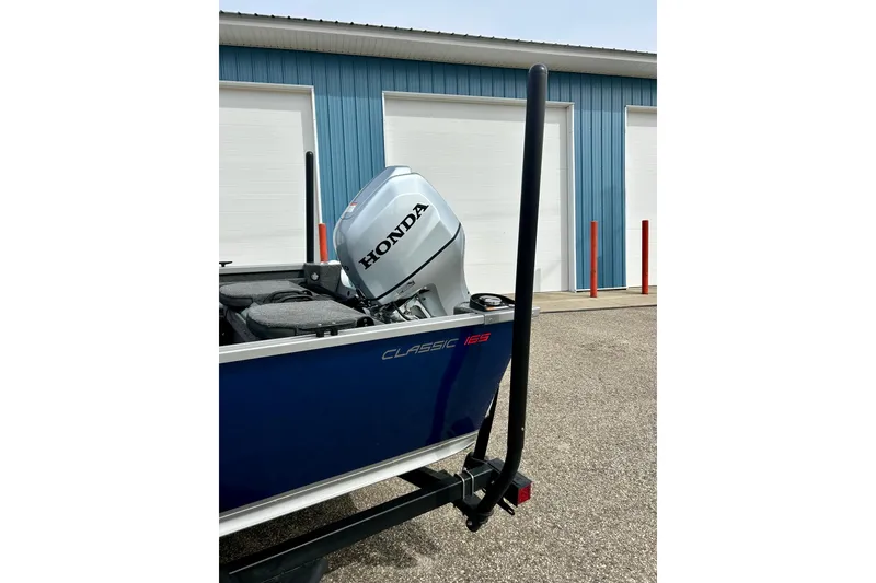 Slide: The Image of 2021 Alumacraft Classic 165 Sport boat with Honda outboard motor, parked near blue building. - 71