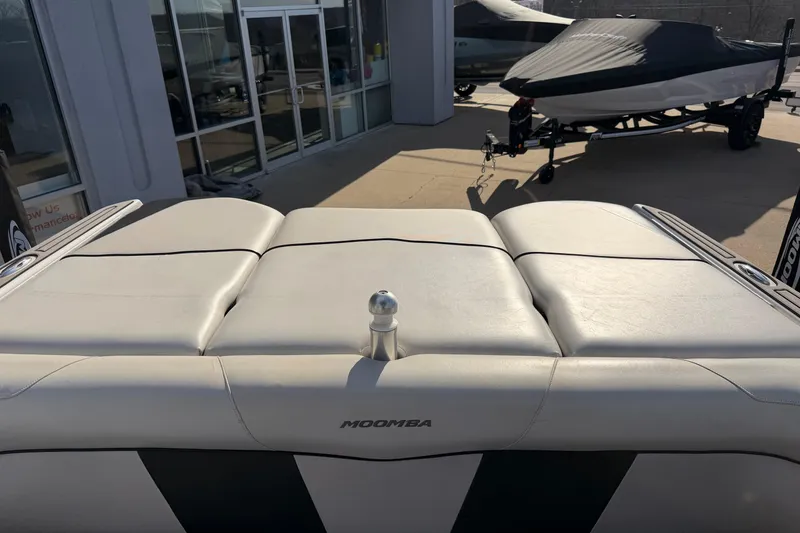 Slide: The Image of 2014 Moomba Mondo boat with cushioned seating, parked near a building. - 13