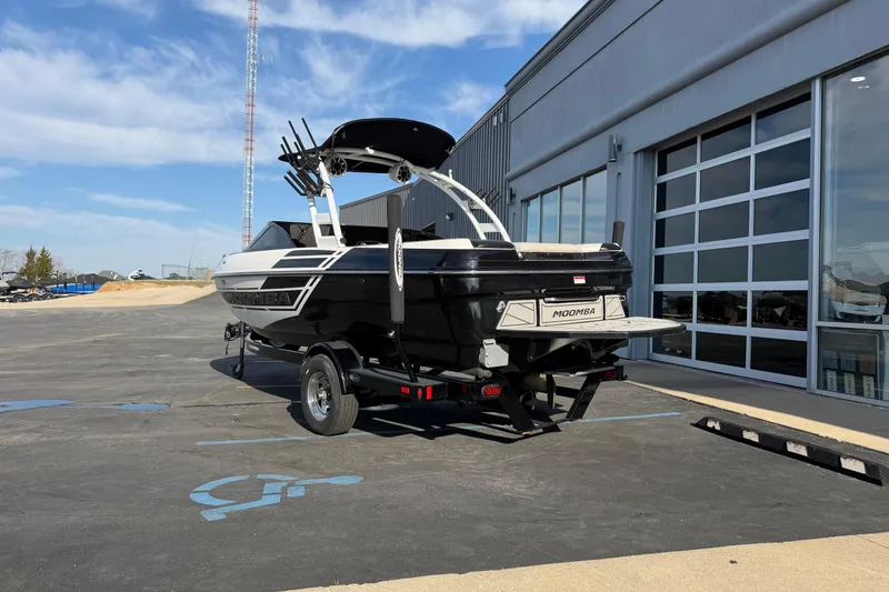 Slide: The Image of 2014 Moomba Mondo boat on trailer outside dealership, clear sky background. - 4