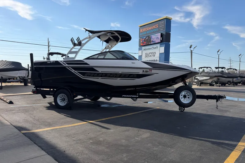 Slide: The Image of 2014 Moomba Mondo boat on trailer at a marine dealership under clear skies. - 8