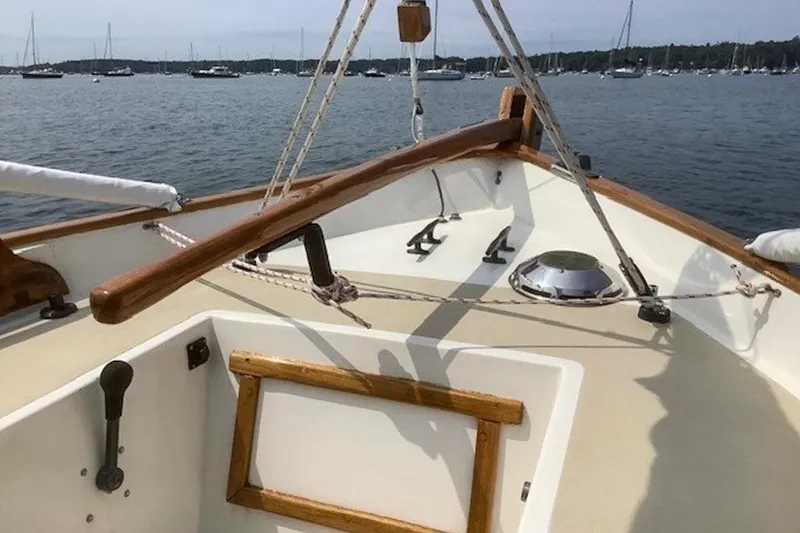 Slide: The Image of 1988 Morris Frances 26 sailboat cockpit with wooden tiller, moored in a scenic harbor. - 11