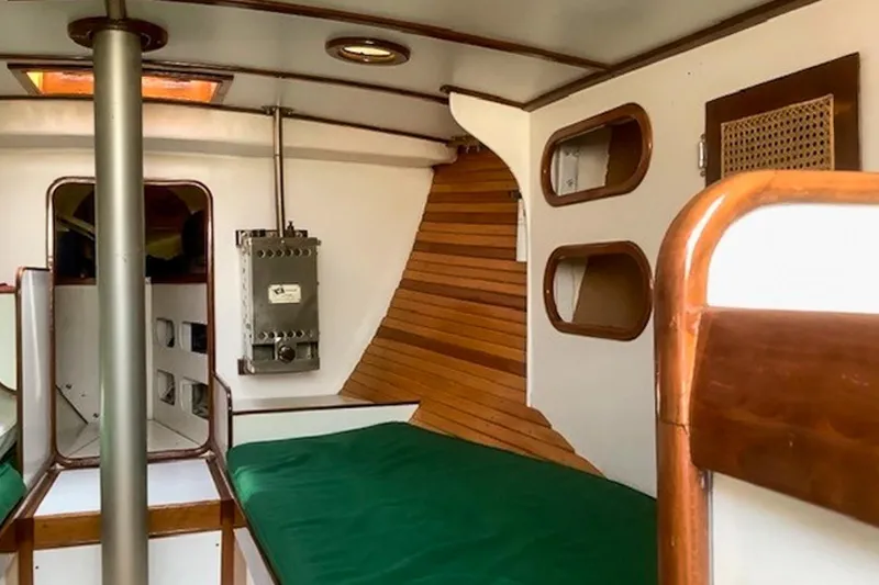 Slide: The Image of Interior of a 1988 Morris Frances 26 sailboat with wooden accents and green bedding. - 18