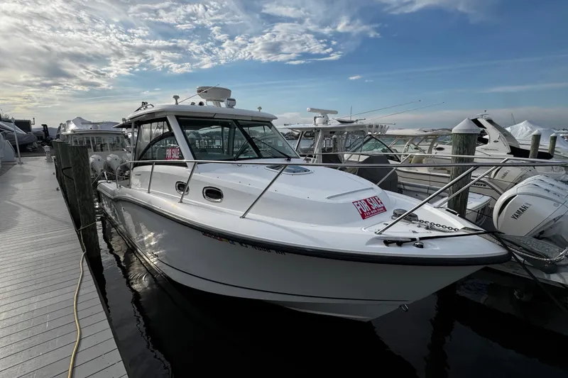 The Image of 2016 Boston Whaler 315 Conquest boat docked, for sale under a partly cloudy sky. - 0