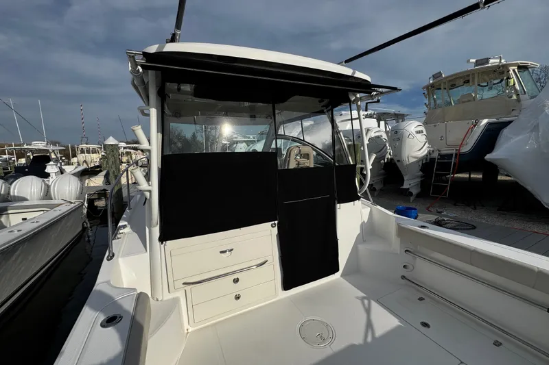 Slide: The Image of 2016 Boston Whaler 315 Conquest boat docked, showcasing rear deck and cabin entrance. - 27